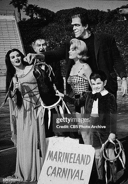 The Munster family stand with a sea lion and a sign for the 'Marineland Carnival' in a still from the TV series, 'The Munsters,' circa 1965. : Actors...