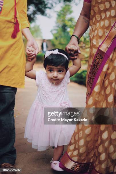 toddler learning to walk holding hands - indian mother daughter stock pictures, royalty-free photos & images
