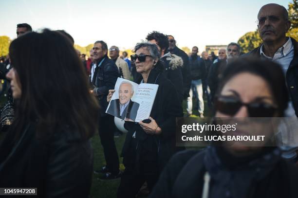 People attend the national homage to the French-Armenian singer-songwriter Charles Aznavour broadcast on a giant screen, on October 5, 2018 at the...