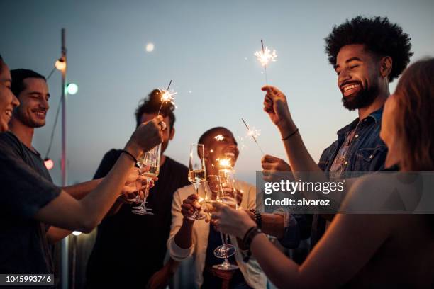 friends celebrating at party on rooftop - sparkler imagens e fotografias de stock