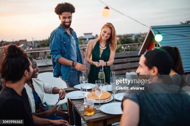 woman opening a champagne at rooftop party - party host stock pictures, royalty-free photos & images