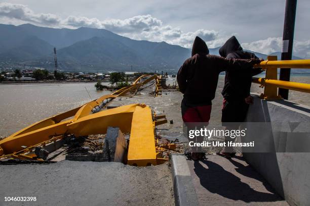 Two man looking at a collapsed bridge which was hit by an earthquake and tsunami on October 5, 2018 in Palu, Central Sulawesi, Indonesia. The death...