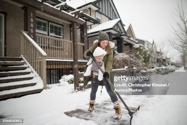 mother with son shoveling snow in winter - canada winter stock pictures, royalty-free photos & images