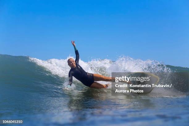 female surfer falling off surfboard while riding wave, male, maldives - hinunter bewegen stock-fotos und bilder