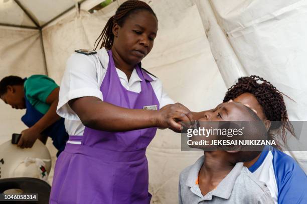 Zimbabwean medical staff gives a young boy a vaccine against cholera during a vaccination campaign on October 5 following a deadly outbreak of the...