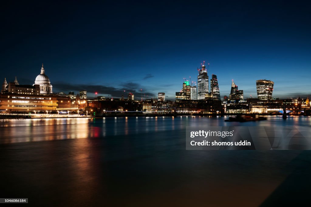 Illuminated city skyline of London across Thames River at twilight