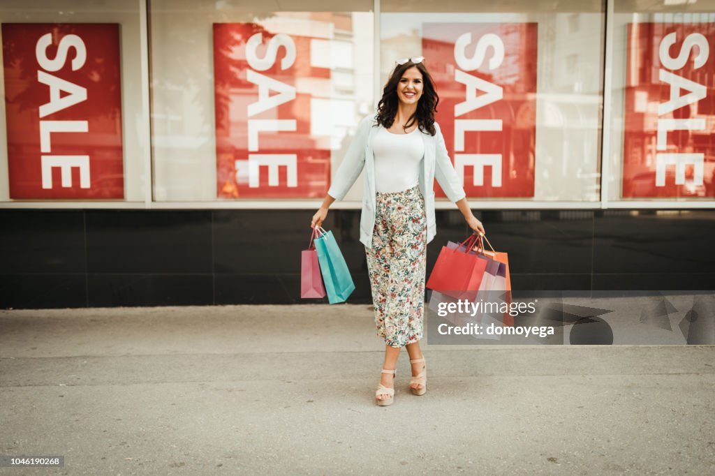 Smiling woman having fun and carrying shopping bags in the city street