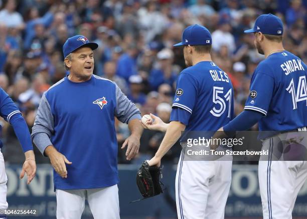 Manager John Gibbons of the Toronto Blue Jays is presented the game ball of the final out by Ken Giles after their victory on his final home game as...