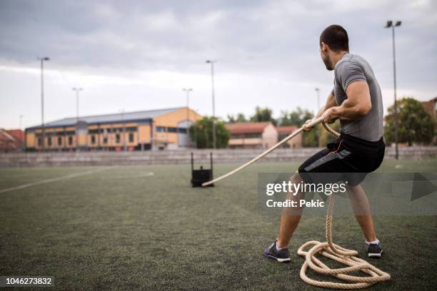 hombre tirando de trineo de gimnasio - pulling fotografías e imágenes de stock