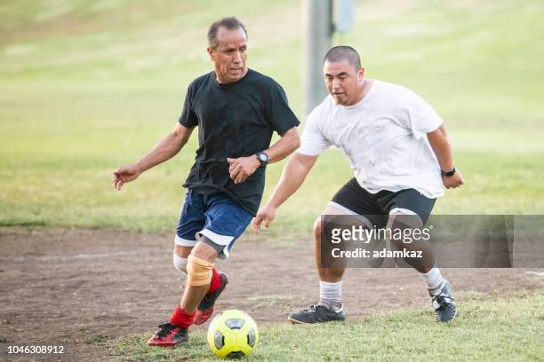 gemengde leeftijd groep latino mannen te voetballen - verdediger voetballer stockfoto's en -beelden