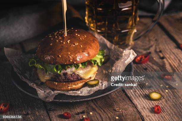 おいしいハンバーガーと木製のテーブルの上のビールのジョッキ - ハンバーグ　皿 ストックフォトと画像