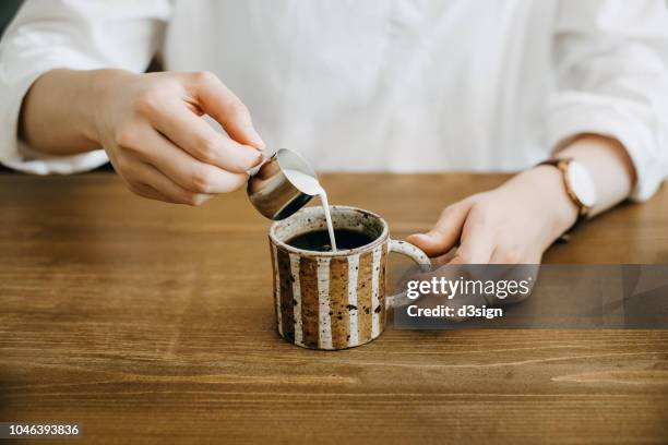 close up shot of woman pouring milk in coffee cup and ready to enjoy it - barista coffee milk stock pictures, royalty-free photos & images