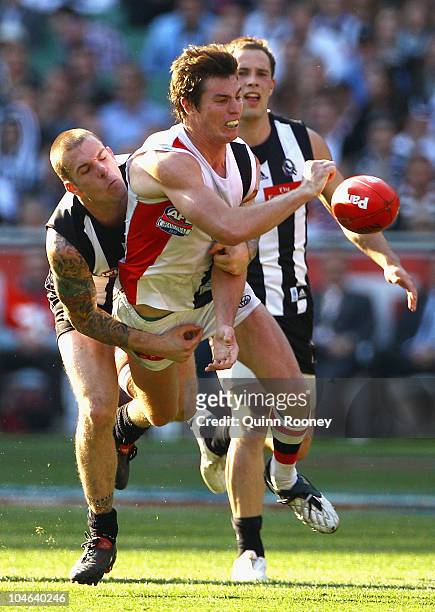 Lenny Hayes of the Saints handballs whilst being tackled by Dane Swan of the Magpies during the AFL Grand Final Replay match between the Collingwood...
