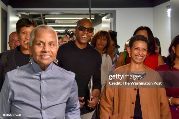 Comedian Dave Chappelle, C, passes through the hallways of Duke Ellington School of the Arts with DC mayor Muriel Bowser, L, and Peggy Cooper...