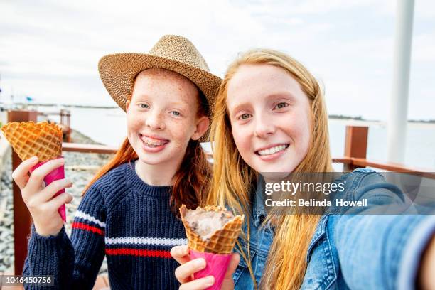 two red headed girls and little boy eat ice cream together by the ocean - boy and girl eating ice cream stock-fotos und bilder