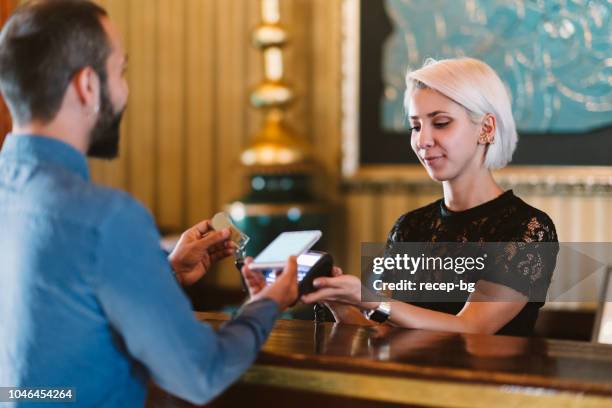 businessman making contactless payment at hotel reception - businesswoman hotel stock pictures, royalty-free photos & images