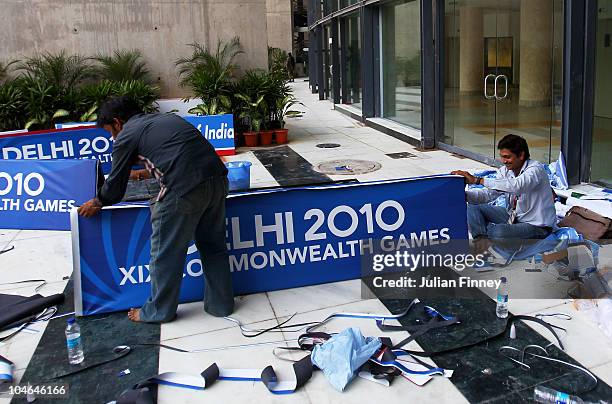 Workmen prepare signage at the Dr. S.P. Mukherjee Aquatics Complex ahead of the Delhi 2010 Commonwealth Games on October 2, 2010 in Delhi, India.