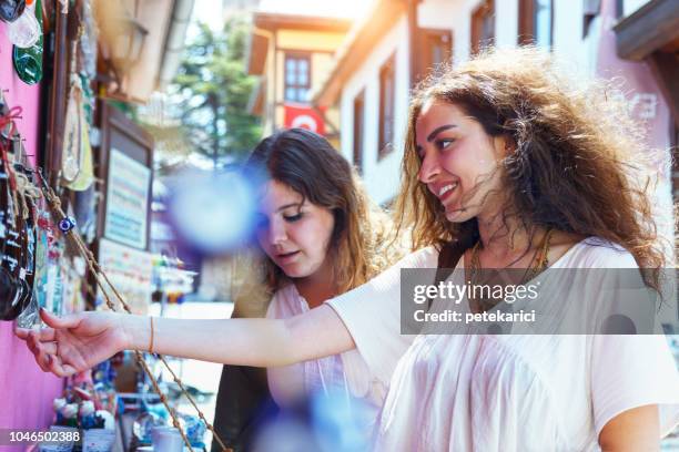 two young friends browsing souvenirs at street market in odunpazari - souvenir stand stock pictures, royalty-free photos & images