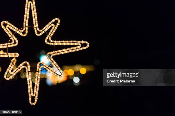 star-shaped christmas light against black sky with city lights in the background. - münchen advent stock pictures, royalty-free photos & images