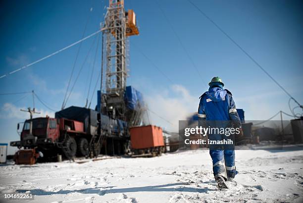 man in a blue jumpsuit walking onto snowy construction site - borehole stock pictures, royalty-free photos & images