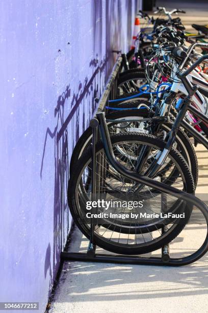 bicycle rack against purple wall - lock sporting position stock-fotos und bilder