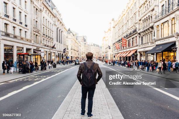 rear view of a man with backpack exploring street of london, england, uk - behind the scenes stock-fotos und bilder