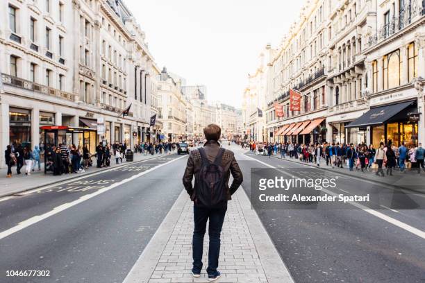 rear view of a man with backpack exploring street of london, england, uk - street shopping stockfoto's en -beelden