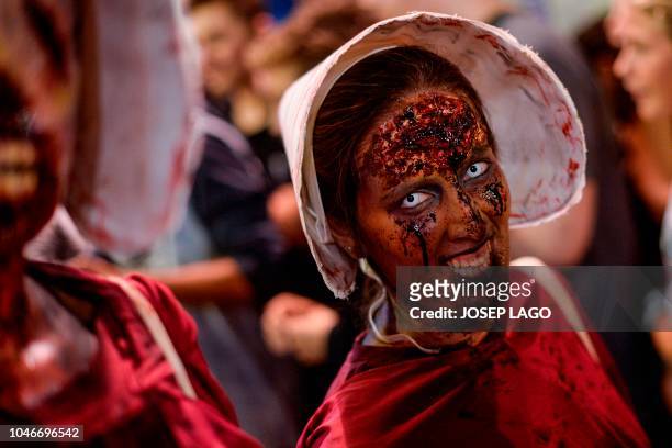 Woman sporting zombie make-up and dressed up as characters of the US TV series "The Handmaid's Tale" take part in the Zombie Walk event on October 6,...