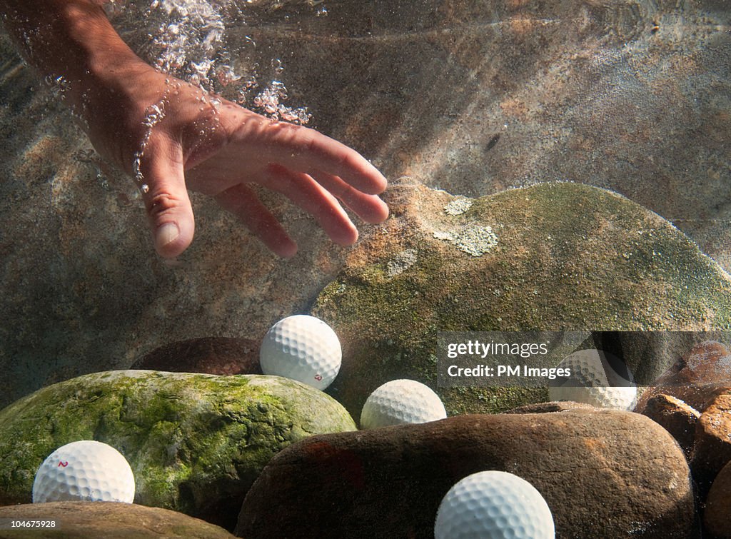 Hand reaching in water for golf balls