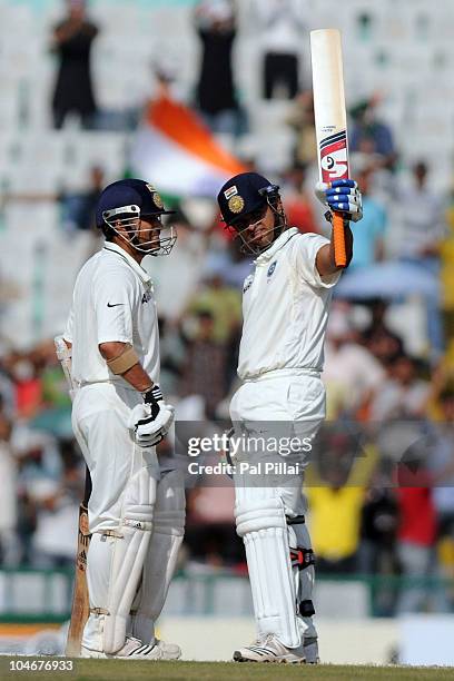Suresh Raina of India raises his bat beside team-mate Sachin Tendulkar after scoring a half century during day three of the First Test match between...