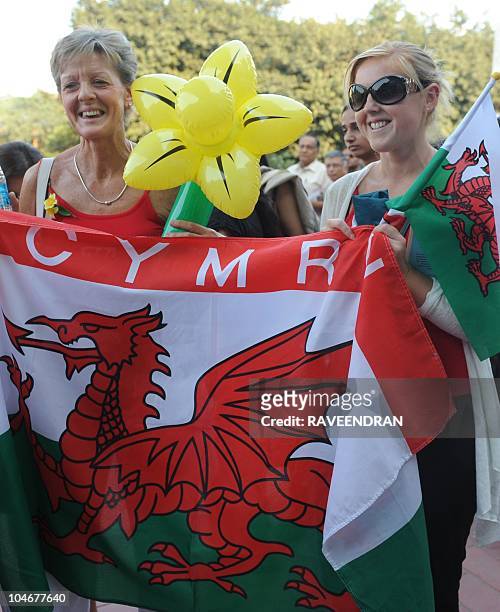 Laura Edwards and Sue Davies , girlfriend and mother of badminton player James Philips of Wales, hold a Welsh flag as they queue to enter the...