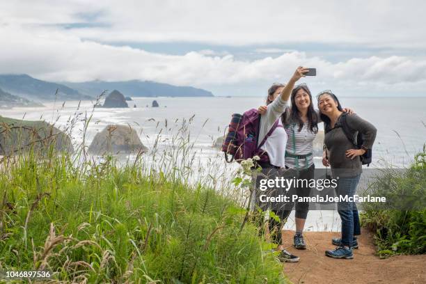 hiking mother, daughters taking selfie from lookout with beach background - cannon beach imagens e fotografias de stock