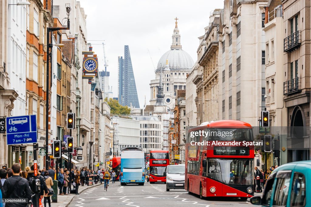 Busy street in City of London with heavy traffic, crowds of people and dome St. Paul's Cathedral