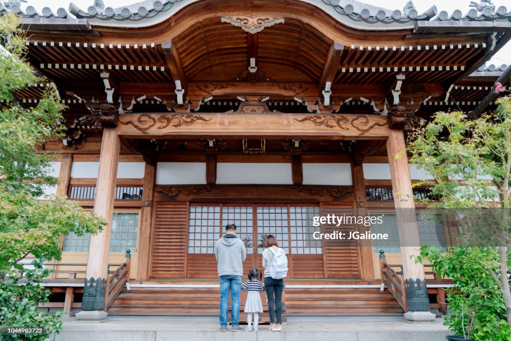 Family of tourists praying at a Japanese Temple