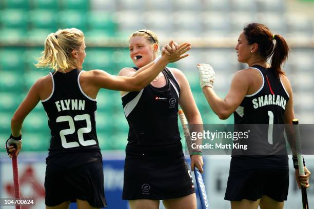 Katie Flynn of New Zealand celebrates her second goal with team mates Gemma Flynn and Kayla Sharland competes in the women's hockey match between New...