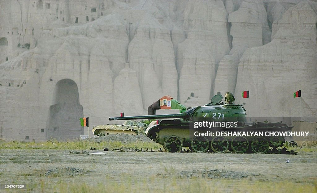 A tank lies in a distant field in front