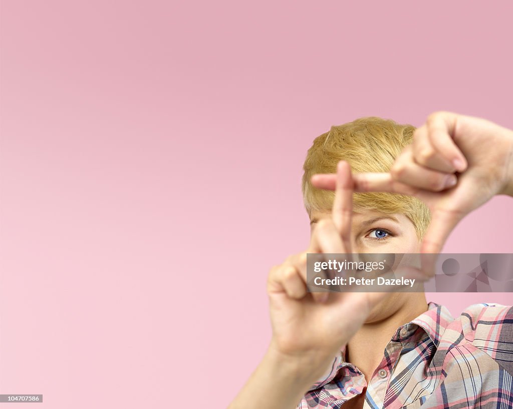 Woman framing with fingers on pink background