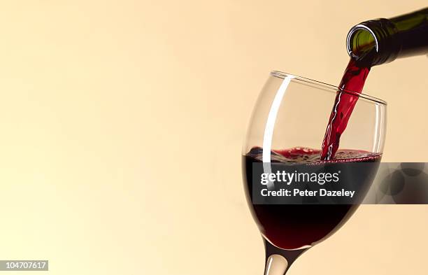 pouring glass of red wine with copy space - red wine glass stock-fotos und bilder