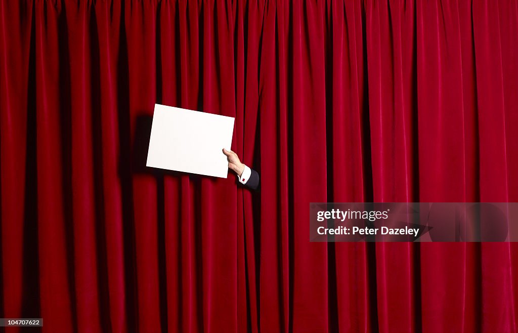 Announcement in front of red theatre curtains