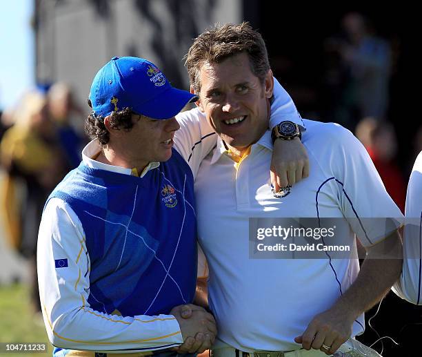 Rory McIlroy of Europe embraces Lee Westwood on the 18th green after he halved his match in the singles matches during the 2010 Ryder Cup at the...