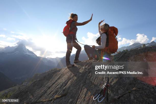 mother and daughter ascend rock cliff, exchange 'high-fives' - achieve woman stock pictures, royalty-free photos & images