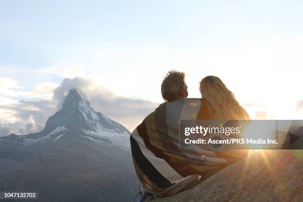 couple relax on rock ledge, nestle into blanket - outdoor guy sitting on a rock stock pictures, royalty-free photos & images