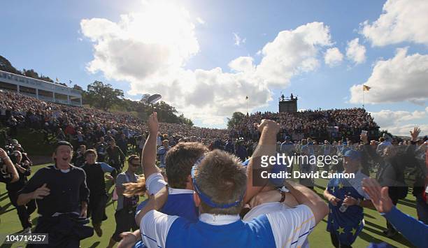 Graeme McDowell of Europe is mobbed by his team mates and caddies after his 3&1 win to secure victory for the European team on the 17th green in the...