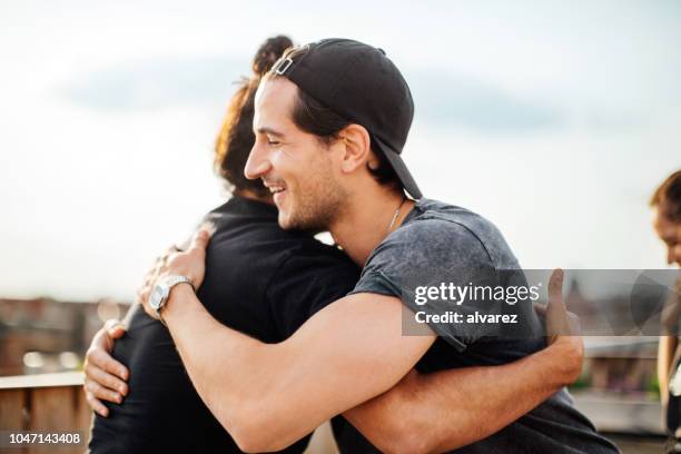 friends greeting each other at terrace party - man embracing stock pictures, royalty-free photos & images