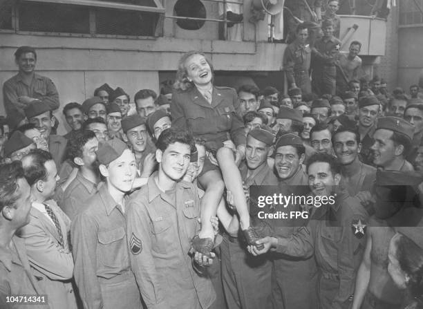 Marlene Dietrich , German-American actress and singer, sitting on the shoulders of returning troops in New York, USA, circa 1945. Dietrich greeted...