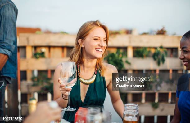 multi-ethnischen freunde mit getränken auf terrasse party - feierabend stock-fotos und bilder