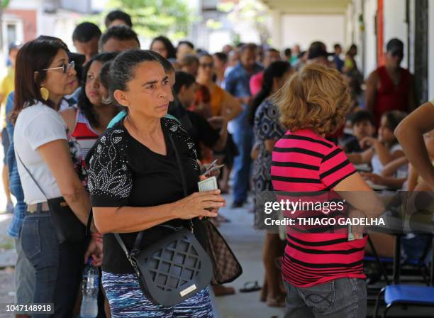 People queue in front of a polling station during general election, in Fortaleza, Ceara state, Brazil, on October 07, 2018. - Brazilians began...