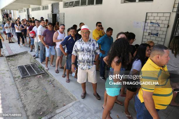 People queue in front of a polling station during general election, in Fortaleza, Ceara state, Brazil, on October 07, 2018. - Brazilians began...