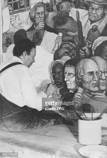 Diego Rivera , Mexican artist, sits finishing a painting, circa 1930.