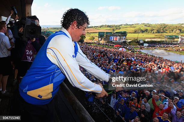 Rory McIlroy of Europe celebrates with champagne on the balcony of the clubhouse following Europe's victory at the end of the singles matches during...